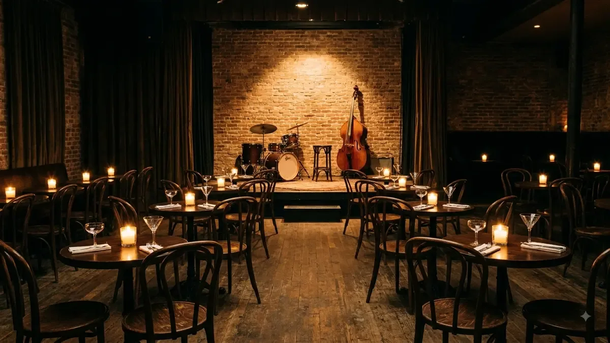 Salon de club de jazz con mesas redondas, velas y un escenario bajo iluminado al fondo
